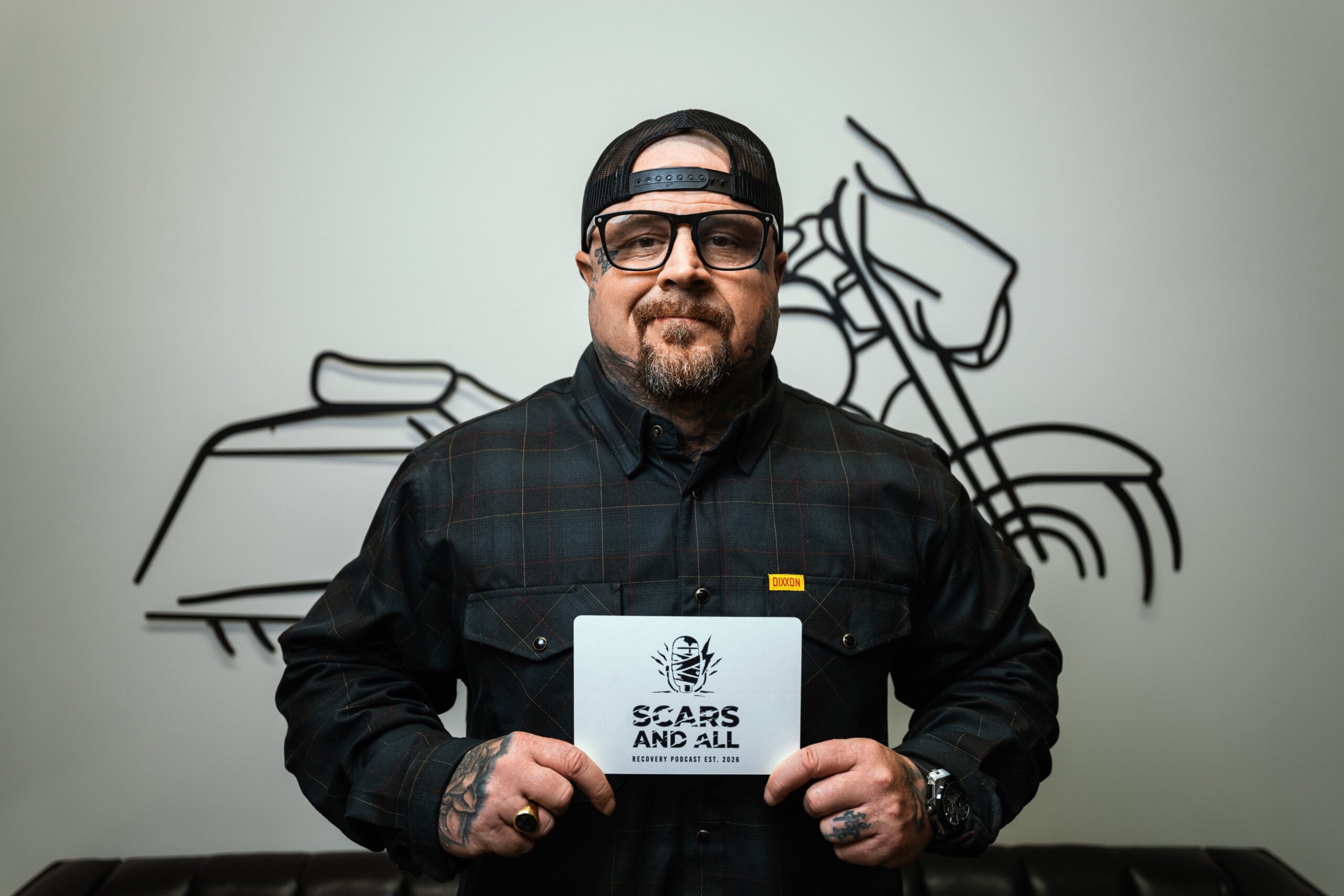 Frank Wills holding the Scars and All podcast sign